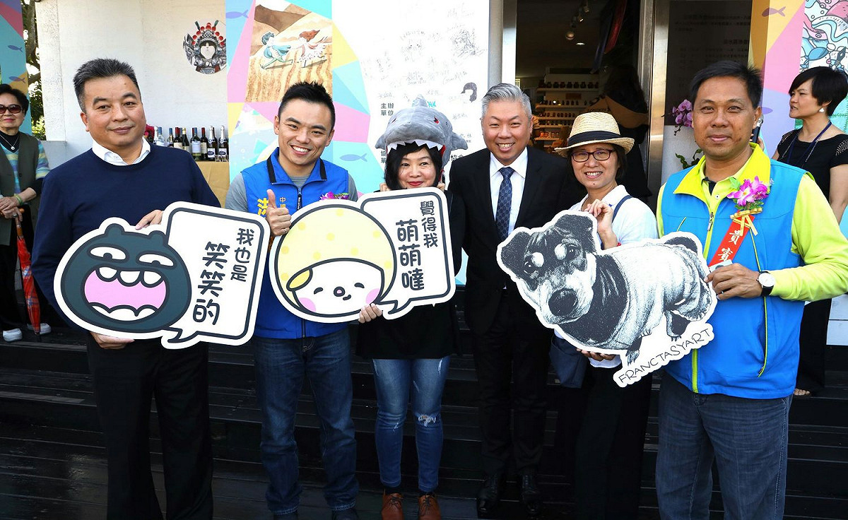 「秀233二館」開幕同時舉辦展覽，淡水區漁會總幹事吳永寬（左一）等人持可愛的手拿牌介紹。  圖：秀之藝術文化社提供