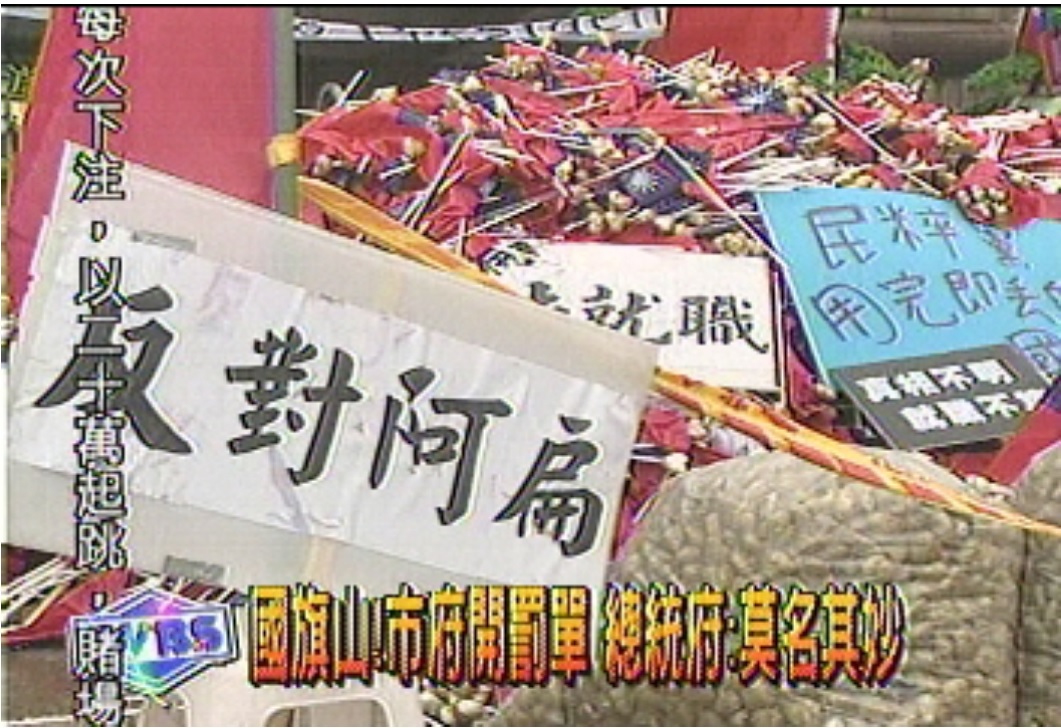 「國旗塚」為2004年之事，「民粹黨用完即丟的國旗」海報清晰可見。 圖：取材自TVBS網站