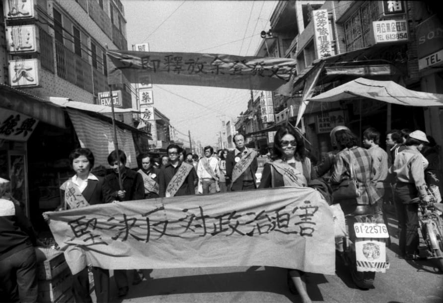 黨外人士到高雄縣橋頭鄉示威抗議遊行，1979年1月22日在余家門前出發，由陳婉真（左）與陳菊手持「堅決反對政治迫害」走在隊伍最前頭，曾心儀與胡萬振高舉要求「立即釋放余氏父子」布條。 圖：陳博文／攝