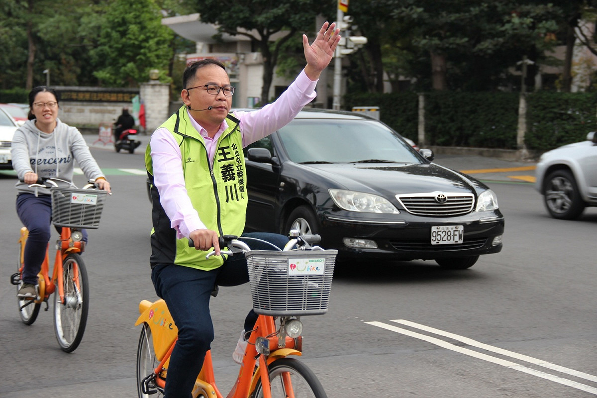 王義川經常騎iBike在選區內拜票。 圖 : 王義川競選總部/提供