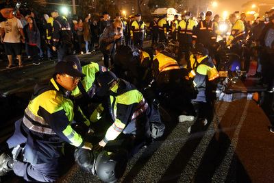 台南1歲多女童疑遭虐死，4名涉案人陸續被裁定收容或 收押；因南檢外民眾群聚，檢院警17日凌晨採調虎離山 之計，送走嫌犯，警方還出手壓制呼嘯而過的騎士。圖 為騎士被壓制在地。 圖：中央社