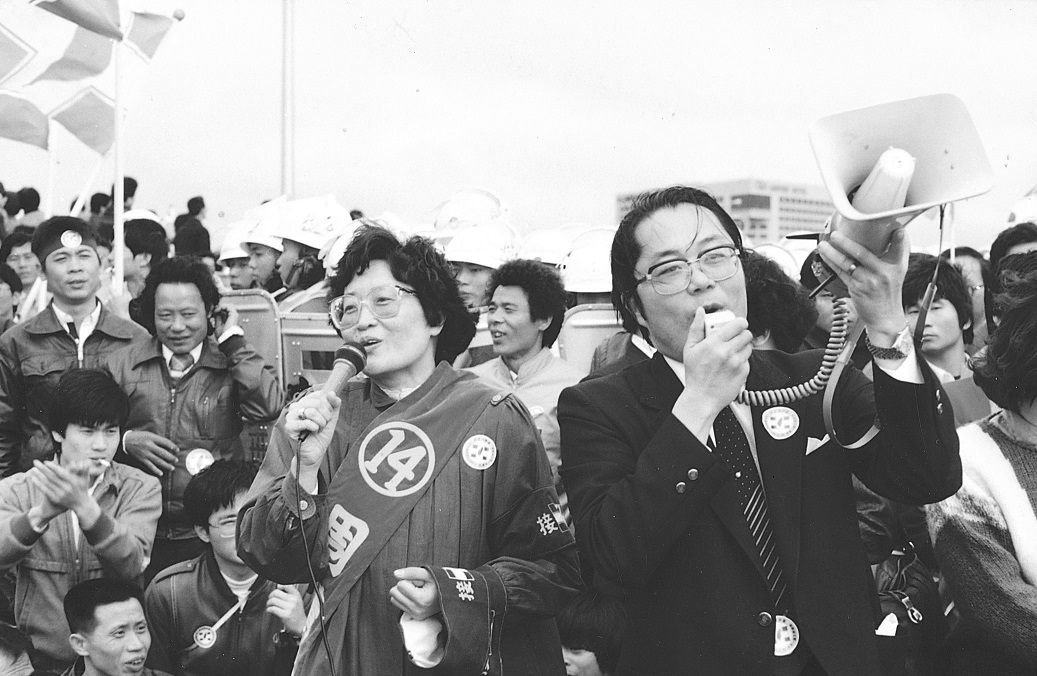 民進黨主席江鵬堅與周清玉國代在鎮暴隊伍前帶領民眾唱「黃昏的故鄉」，安撫被催淚瓦斯襲擊的現場民眾。 圖：邱萬興／攝（資料照片）