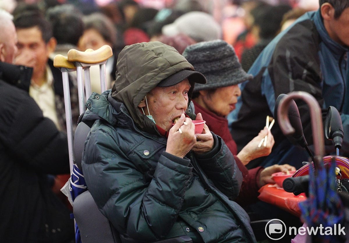 一位參加寒士30愛心尾牙的長者享受創世基金會等團體準備的熱呼呼美食。 圖：張良一/攝