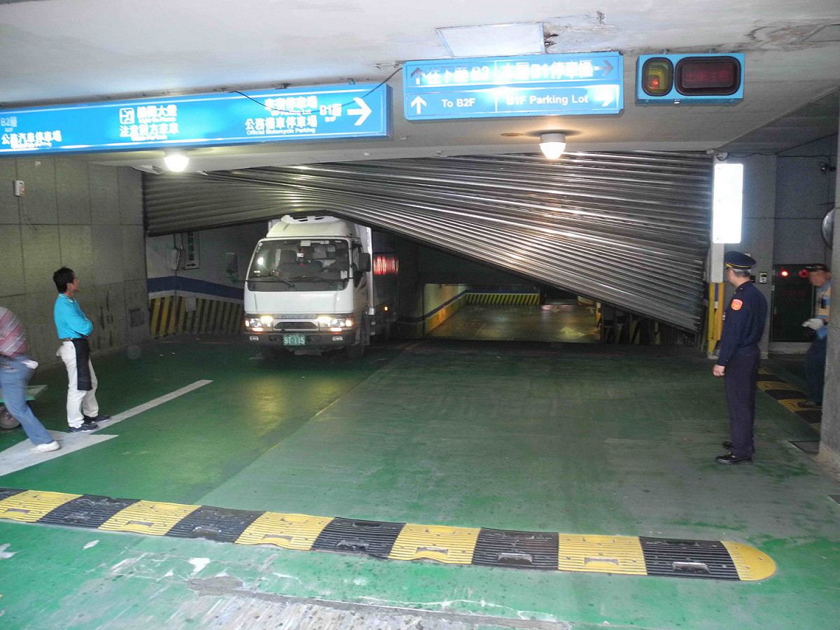 新北市府地下停車場B2到B1的西側入口處大型鐵捲門，今早突然墜落砸中冷凍車，西側車道整個封閉。  圖：王峻昌/攝