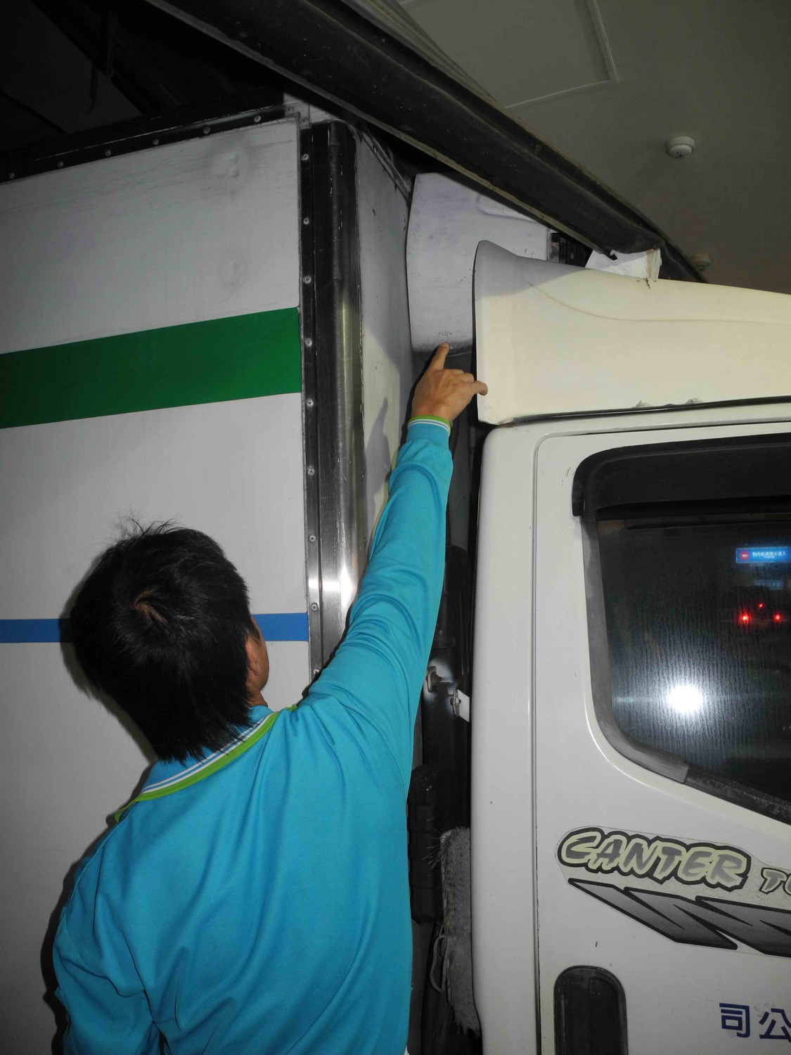 超商冷凍貨車的陳姓司機，心有餘悸地指著車頂被砸中的冷凍機。  圖：王峻昌/攝