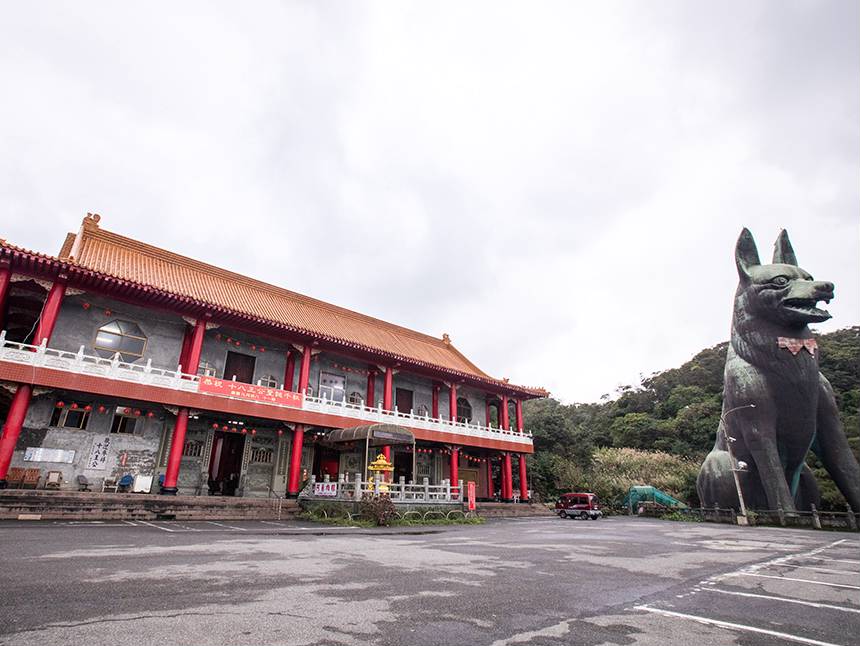 新十八王公廟位於半山腰，四周景緻優美，其中最大特色是，廟旁蹲坐一隻約有十層樓高的「黑龍義犬」塑像。 圖：取自新北市觀光旅遊網