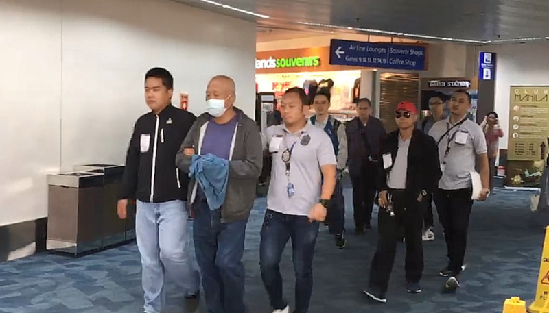 在台涉及職棒打假球案而被通緝的前台南縣議長吳健保，6日由刑事局人員以及駐菲聯絡官共同從馬尼拉國際機場押回台北，過程有戴手銬但以毛毯遮蓋。 圖：菲律賓移民局人員提供