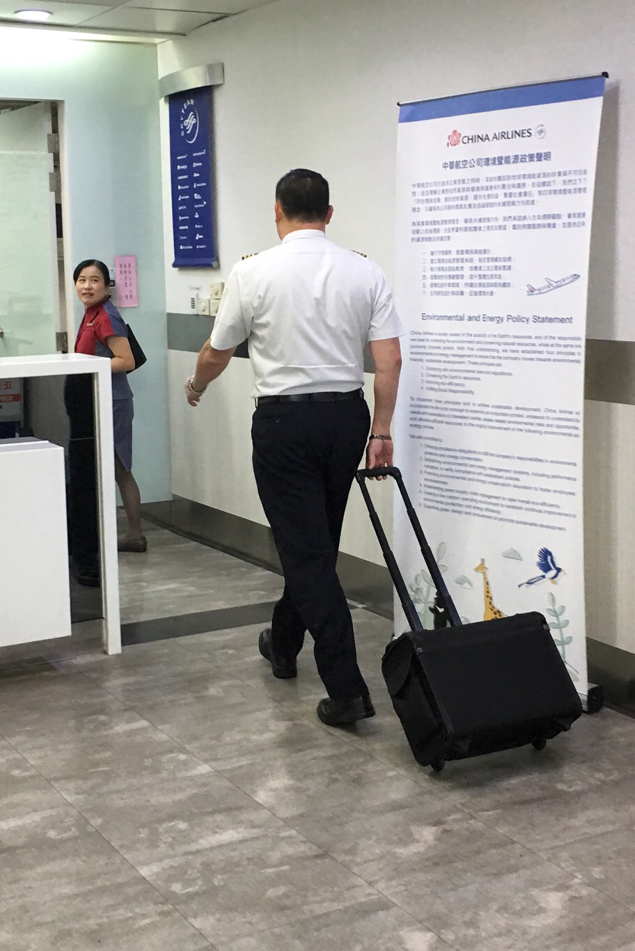 一位沒有參與罷工的華航機師拉著行李箱走進高雄小港國際機場出境大廳時，經過空蕩蕩的華航報到櫃檯，準備執勤。 圖：張良一攝