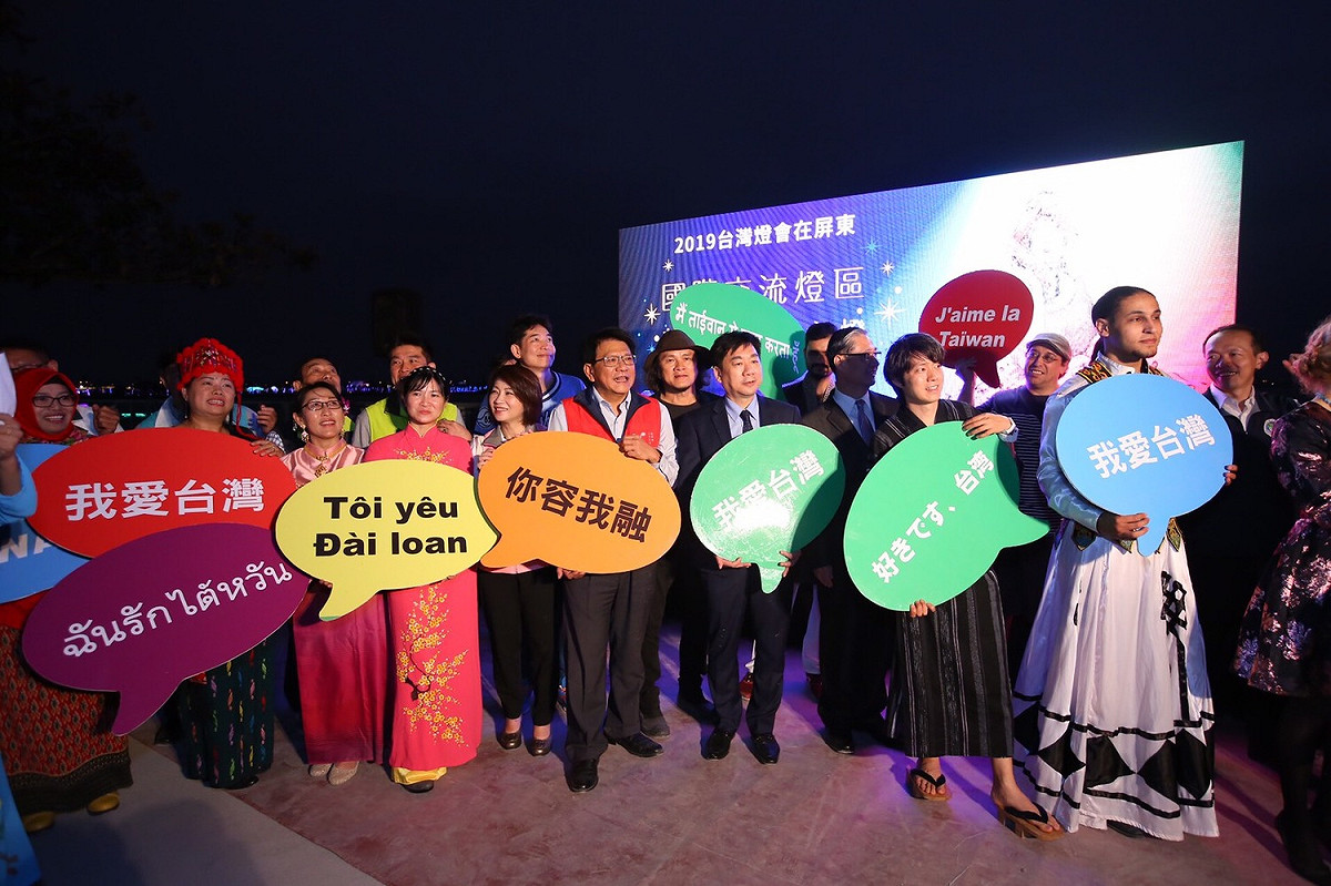 縣長潘孟安（紅背心）、內政部次長陳宗彥（打領帶）與現場來自各國的新住民姐妹齊喊：「我在台灣，我很好！」 圖：屏東縣政府提供