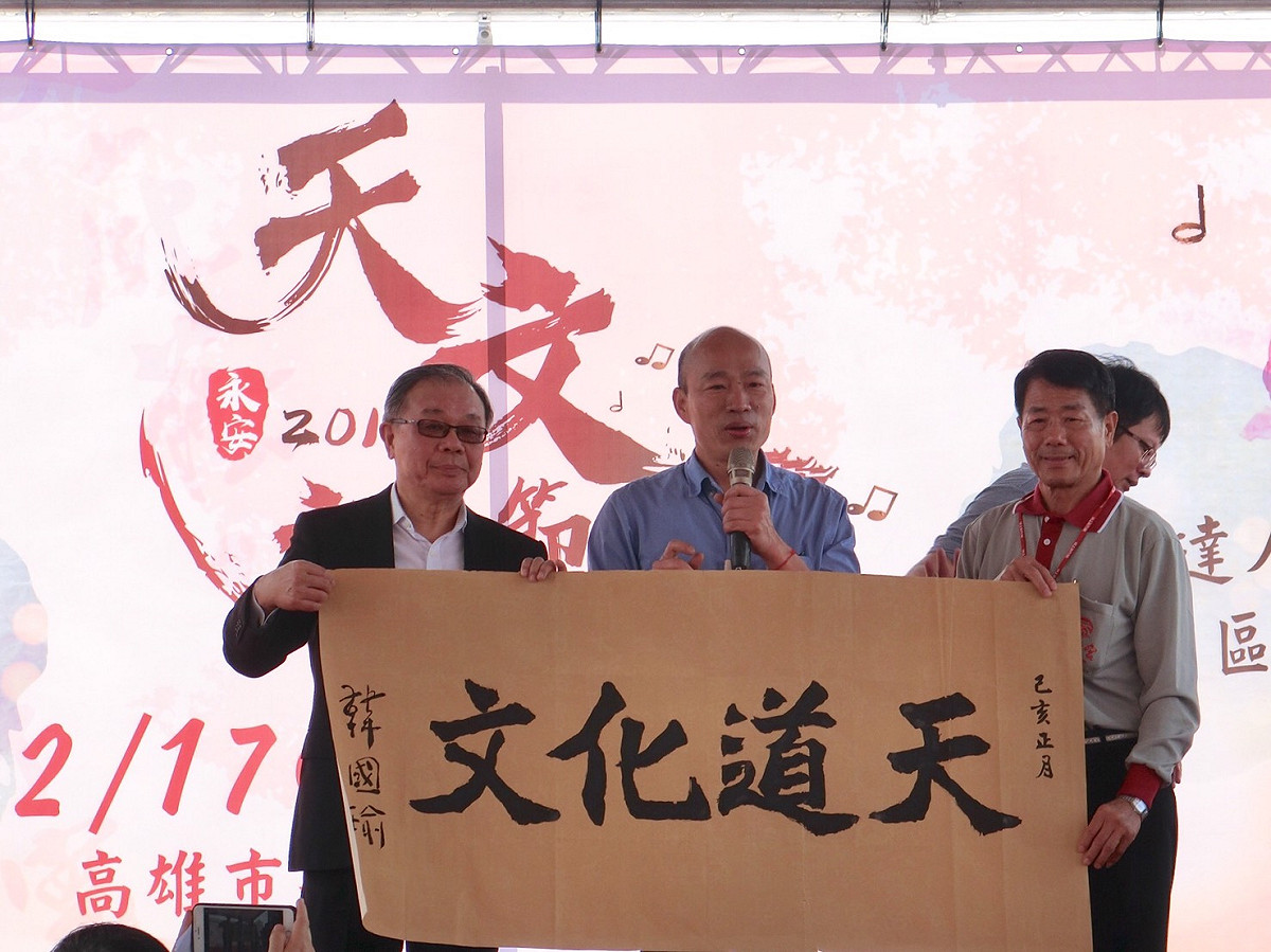 韓國瑜(左二)在廟方準備的「天道化文」題字上落款。 圖：高雄市新聞局／提供