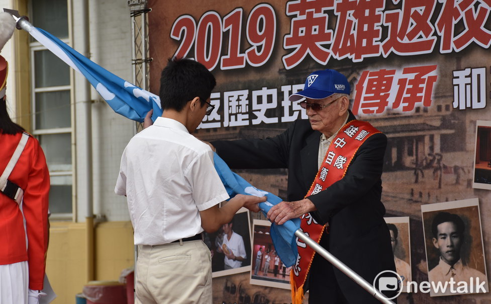 雄中自衛隊副隊長陳仁悲(右)授雄中校旗給學生代表，象徵世代傳承的意義。 圖：孫家銘／攝