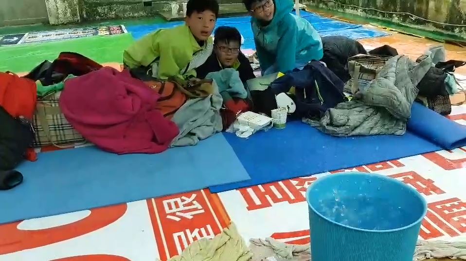 桃園市立游泳池室內漏水嚴重，還出動水桶接水，整個休息區隨處可見選手在潮濕的地板上，墊著帆布墊或隔水布休息。 圖：詹江村／提供