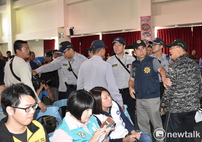 著迷彩服的反輕軌民眾(右一)與支持輕軌的民眾隔著警方人牆叫陣。 圖：孫家銘／攝