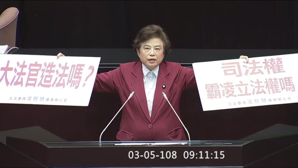 「中國法政大學」法學博士的立委沈智慧，在立法院手持「大法官造法？」與「司法權霸凌立法權嗎？」標語質詢。 圖：擷取自沈智慧臉書