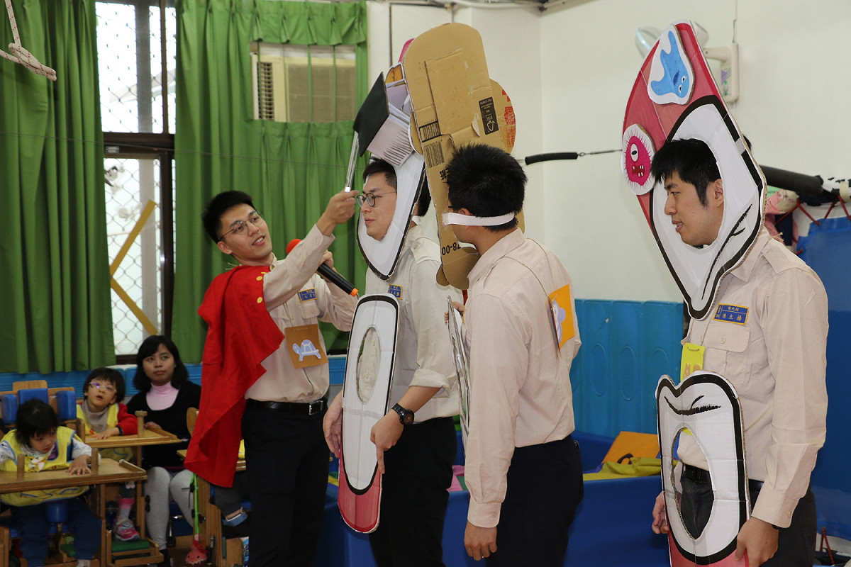 台大牙醫系且考取牙醫師的沈育葳(左)扮演超人，和其他替代役男為慢飛天使進行口腔衛教。  圖：新北市社會局/提供