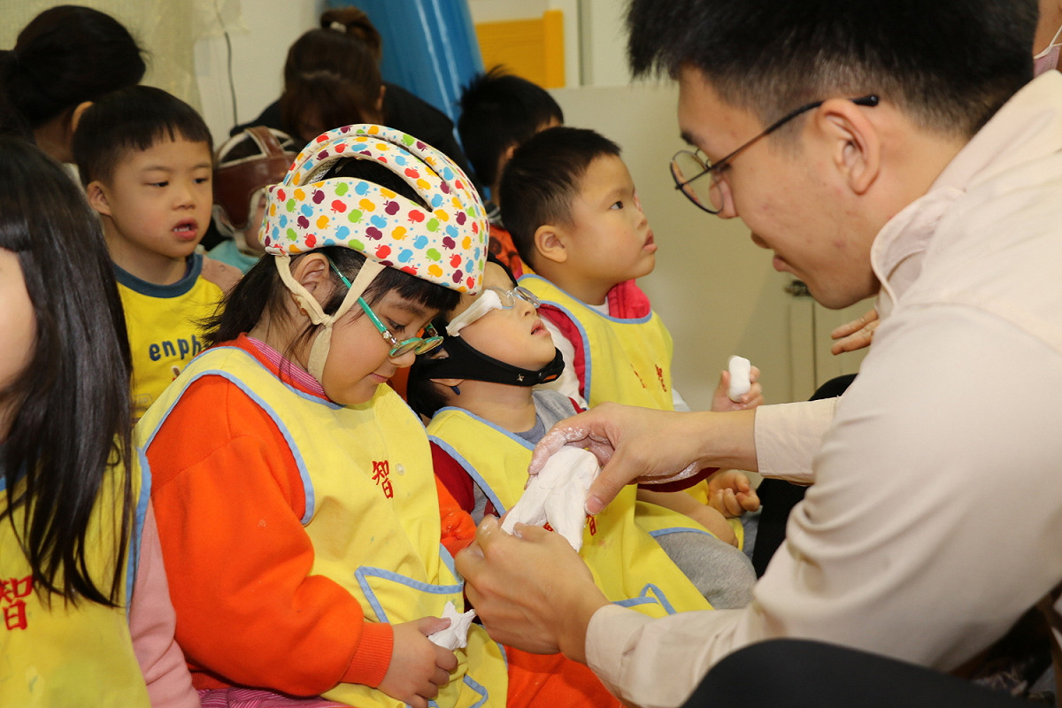 替代役男教慢飛天使用紙黏土製作牙齒。 圖：新北市社會局/提供