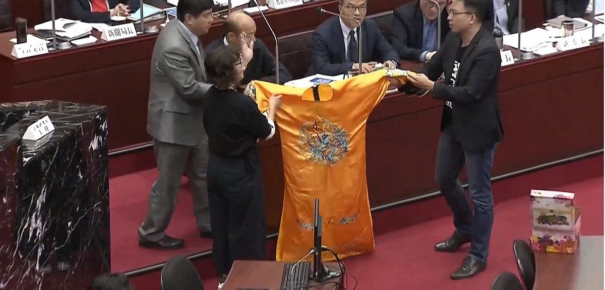 高雄市議會今日開會時，民進黨團總召李喬如及市議員黃文益準備了一件黃袍送給高雄市長韓國瑜。 圖：翻攝自youtube。