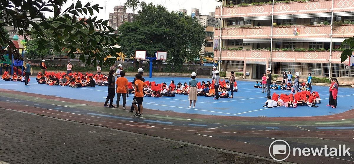 今天中午地震後，北市忠義國小小朋友戴上橘色的防災頭套，在操場防災。 圖：張良一/攝