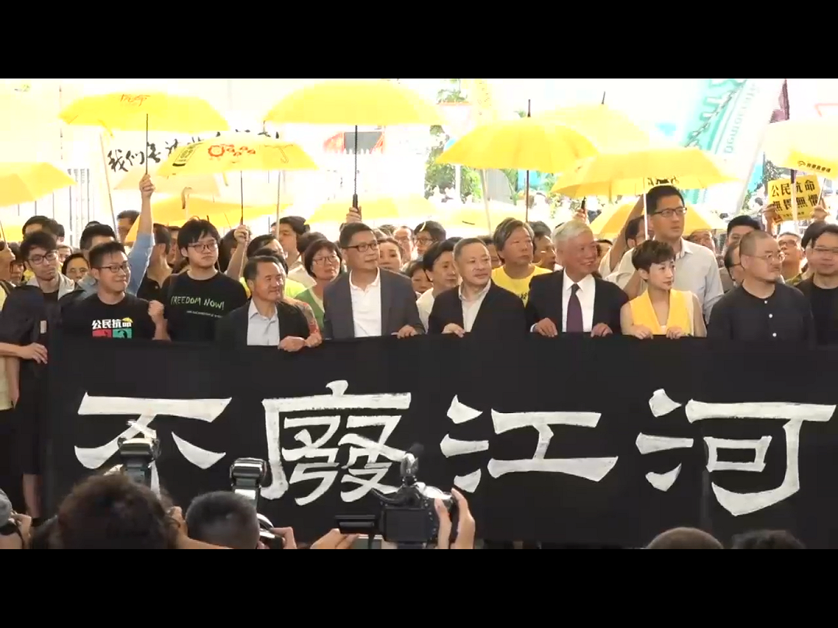 各被告今早陸續到達西九龍裁判法院聽取判刑時，均手持印有「不廢江河萬古流」的黑色橫幅。 圖：翻攝自Youtube