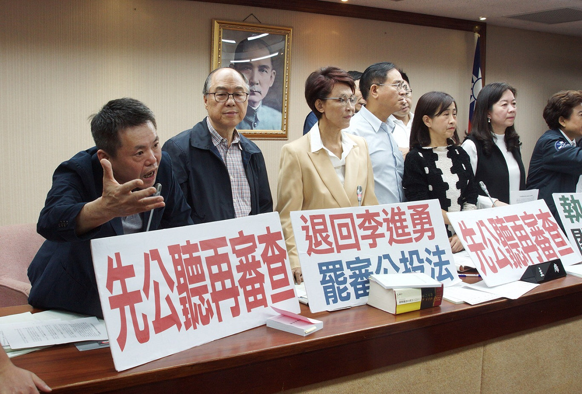 藍委「甲動」突襲委員會，上午8點40分佔據主席台、質詢與備詢台，高呼「退回李進勇，罷審公投法」、「退回鳥籠公投」。 圖：張良一/攝