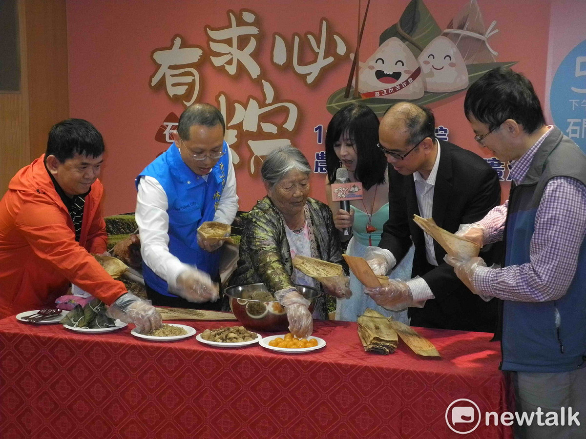 94歲資深肉粽達人林蜂阿嬤指導民政局副局長范姜坤火、石門區區長林俊宏及現場貴賓包肉粽，一展好手藝。  圖：王峻昌/攝