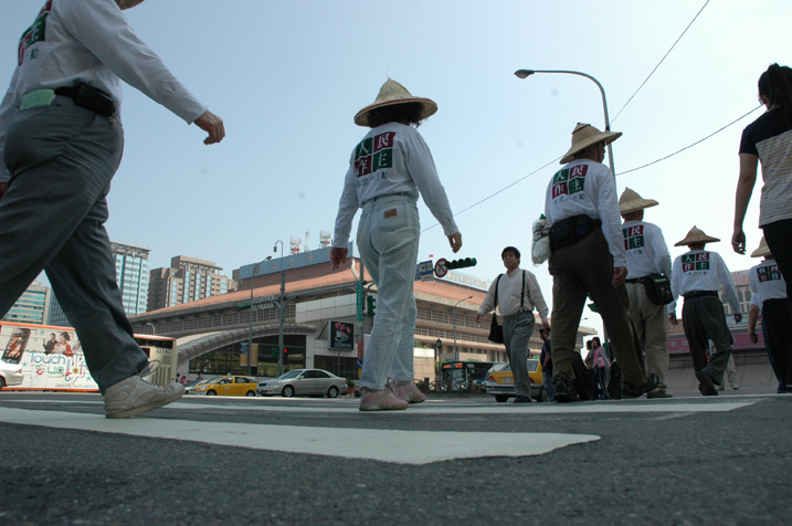 參與運動的人士頂著烈日，一步一步行經台北車站，身旁的車潮來來往往。 圖：邱萬興/攝影