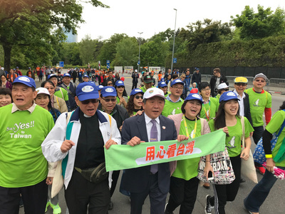 衞福部長陳時中（前左3）19日參與世界衛生組織舉辦的一場健走活動，並手持「用心看台灣」布條。 圖：中央社