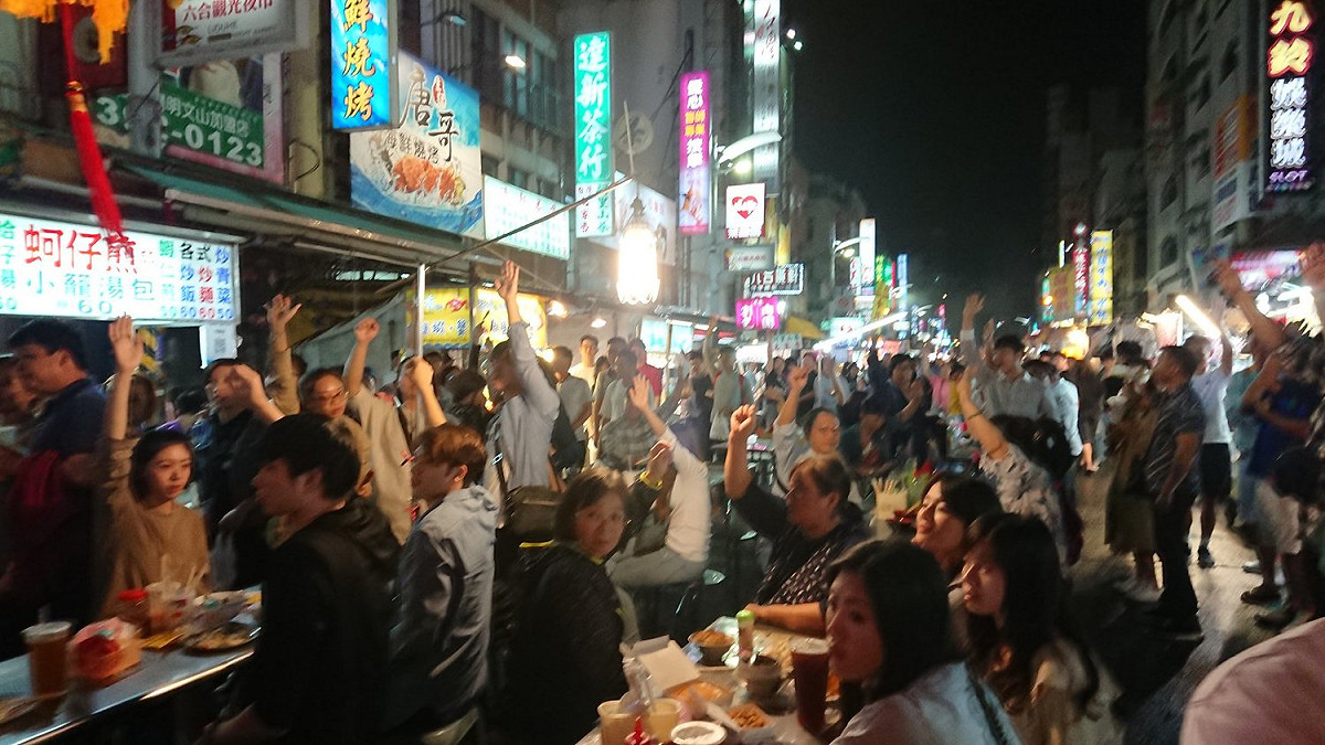 從事美術設計的工作人員陳炫劭貼出去年於六合夜市取景的日本化妝品廣告幕後照片，現場約一兩百個臨演，副導在要控場時，喊了聲臨演舉手。 圖：翻攝自陳炫劭臉書