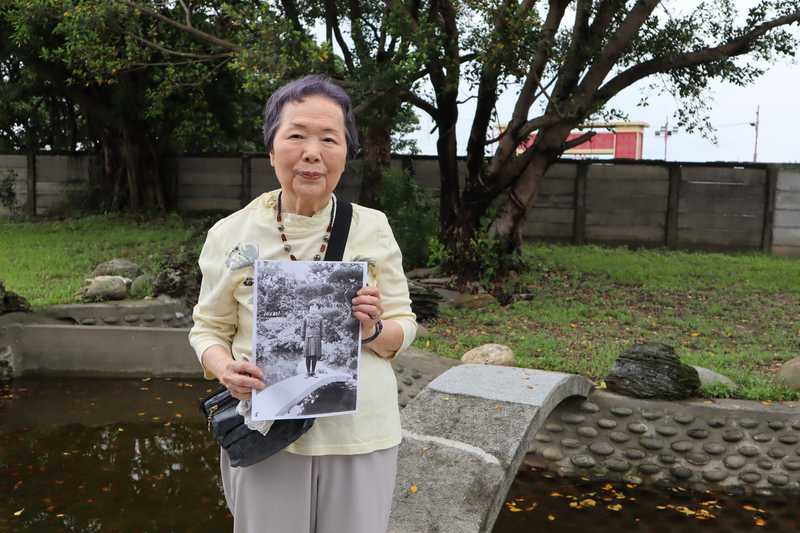 時隔83年，灣生今泉光子25日回到花蓮，在台鐵花蓮管理處處長官邸流連，踏上庭園、水池小橋，看著庭院中種的大榕樹，拿出8歲時的照片比對。 圖：中央社提供