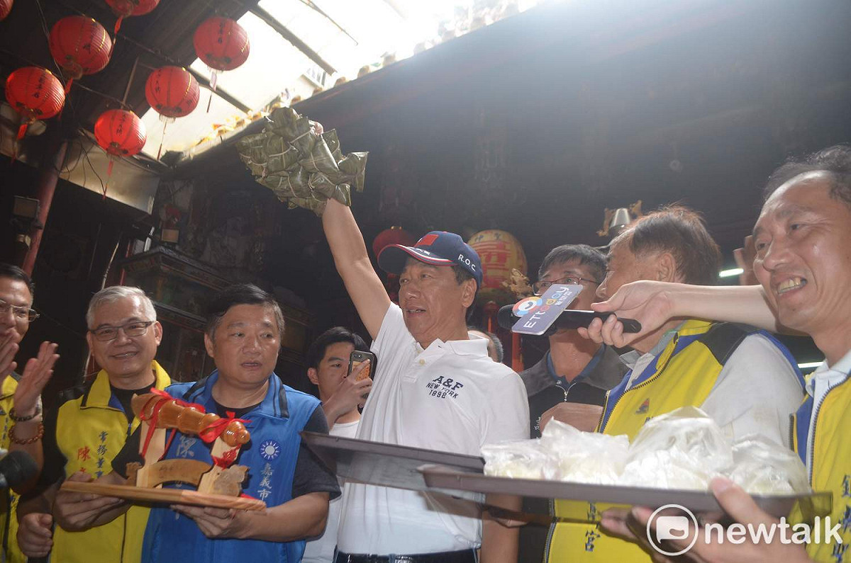 郭台銘在廟前高舉包子和粽子，象徵總統初選「包中」。 圖：蔡坤龍/攝