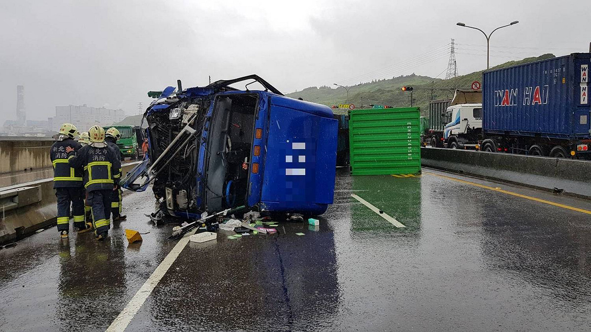 １輛聯結車疑似天雨路滑，在台61線與林口區東華路口南向車道撞上中央分隔島後翻覆，事故現場佔據3個車道。 圖：蘆竹分局／提供