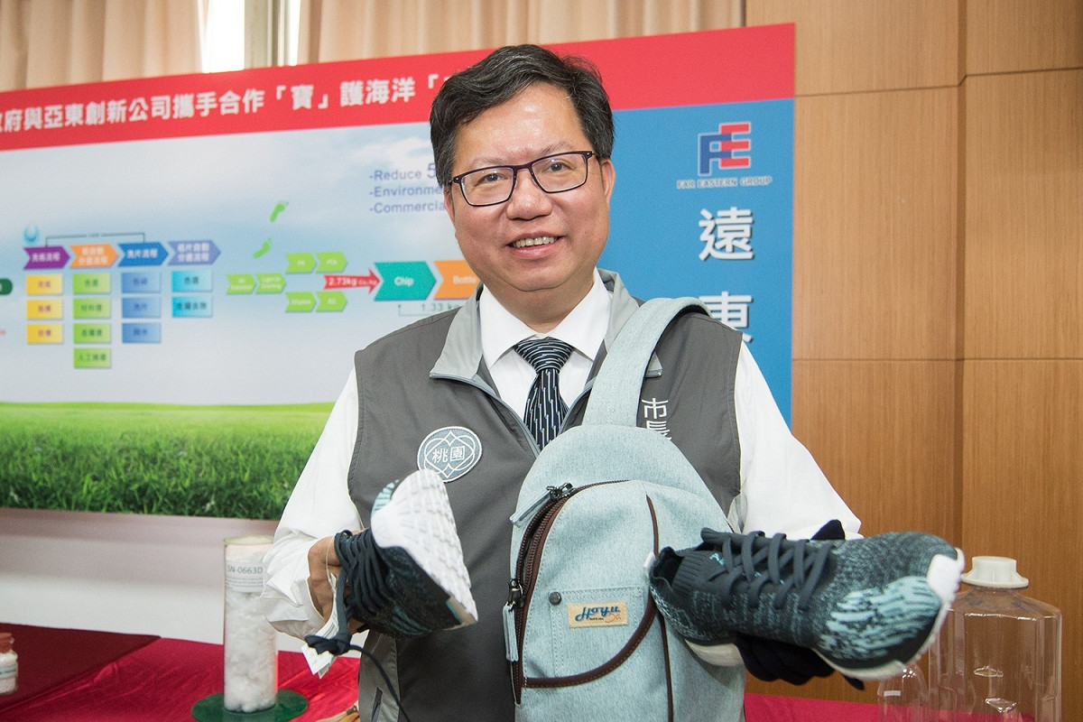 桃園市長鄭文燦手中拿的鞋子和背包都是利用廢棄寶特瓶再生的環保物品。 圖：桃園市政府/提供