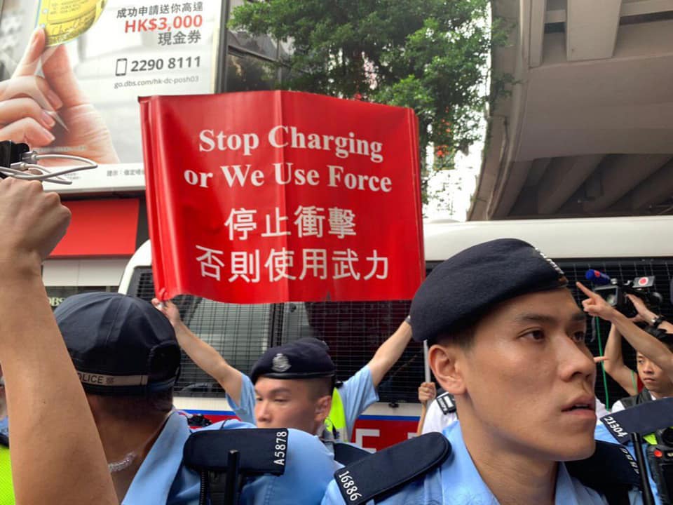 鵝頸橋橋底，警員高舉警告標語維持秩序。  圖：翻攝自全球集氣反送中臉書粉絲頁