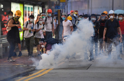 香港12日因為逃犯條例修訂草案二讀，大量民眾聚集抗議，警方下午4時後陸續向民眾發射催淚彈意圖驅離， 部分穿戴護具的抗議民眾想撿起催淚彈。 圖：中央社