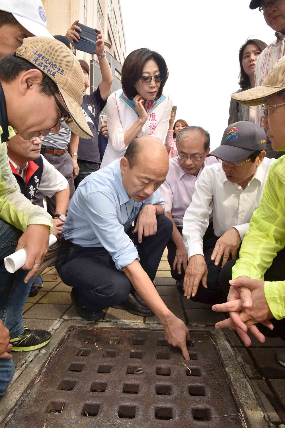 韓國瑜蹲下查看水溝，康裕成在後緊盯。 圖：高雄市政府／提供