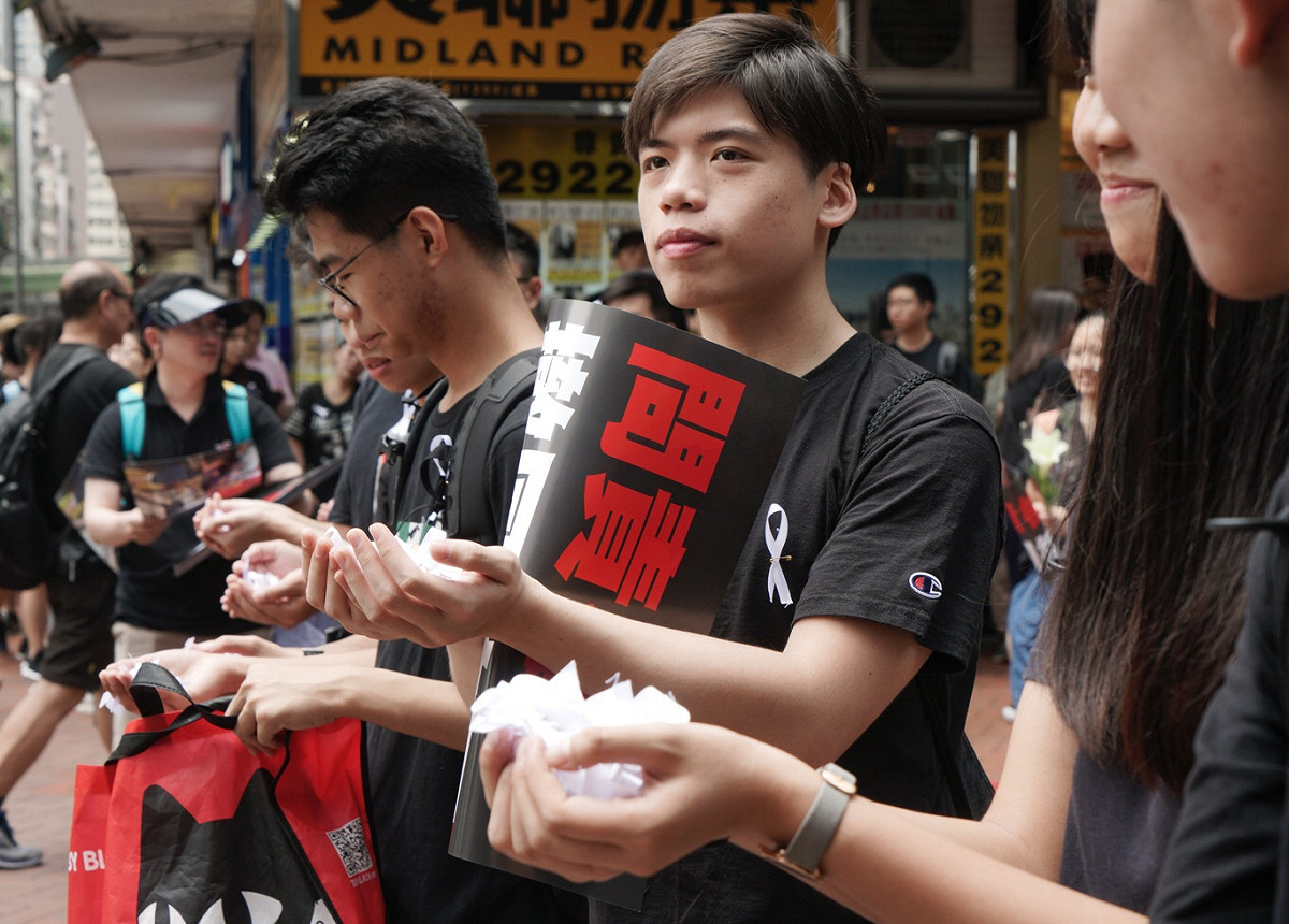 年輕人發放白絲帶紀念昨晚不幸墜樓的反送中青年 圖：張良一/攝