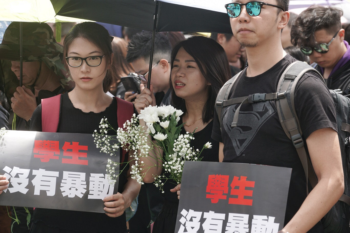 港人著黑衣戴白花參與遊行。 圖：張良一/攝