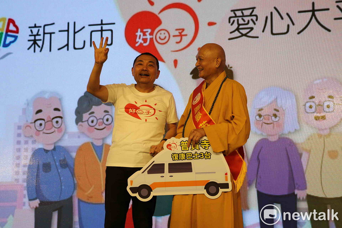 普賢寺宗道法師在愛心大平台啟動儀式，宣布除了原捐3輛復康巴士，另加捐3輛高頂救護車，侯友宜比3讚許。  圖：王峻昌/攝