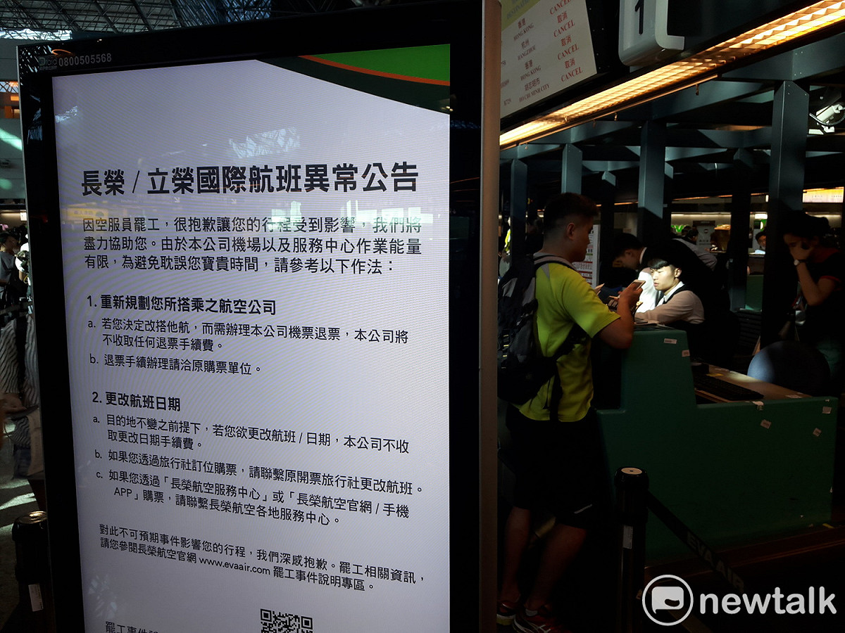長榮航空櫃台人員正在向旅客說明航班取消資訊。 圖：林昀真／攝