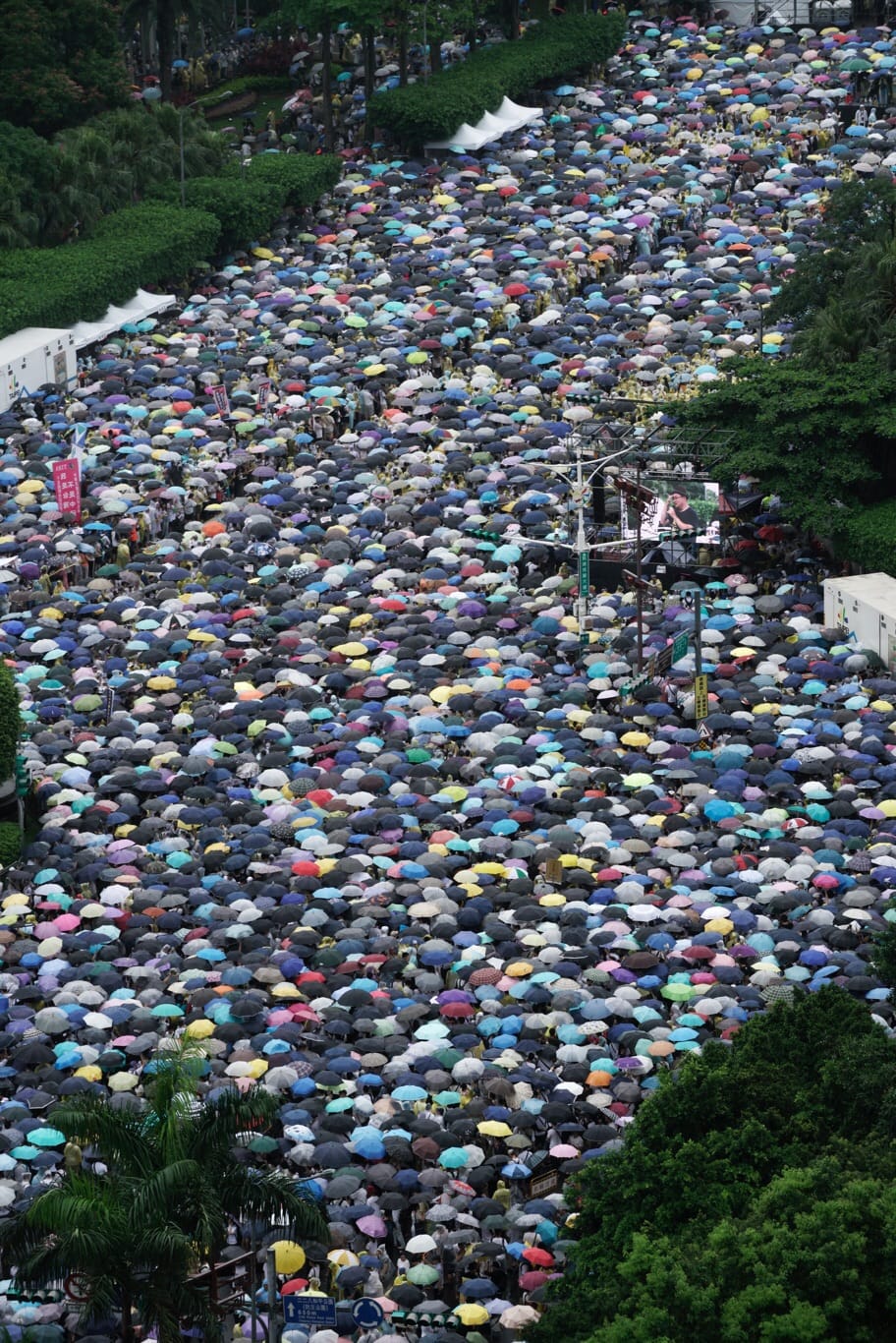 今天下午時陣雨，參與反紅媒遊行的民眾，不畏風雨撐起傘、穿起雨衣，一同站在凱道。 圖：張良一/攝