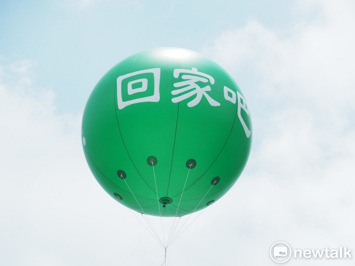 長榮航空公司南崁總部大樓屋頂升起汽球，上頭寫著大大的「回家吧」呼籲在門口集結的罷工會員結束罷工趕快回家。 圖：林昀真/攝