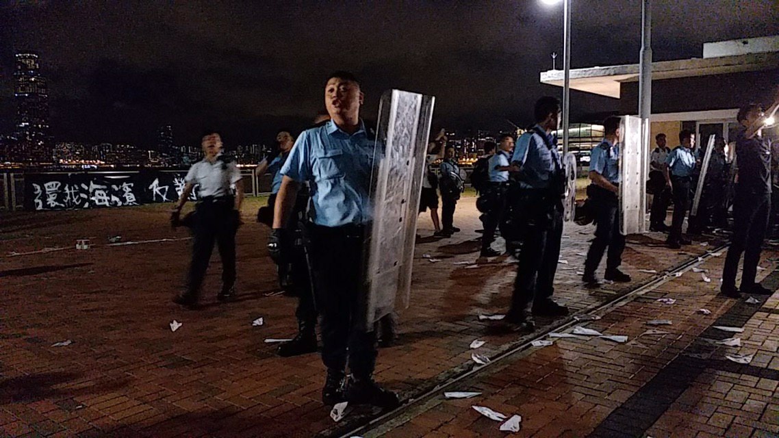 香港民眾昨晚聚集在中環海殯抗議，與警方爆發衝突。圖為港警初至抗議現場，後方可見「反送濱」標語。 圖：取自臉書粉絲專頁「廢青事務委員會 Commission of Weird Youth」