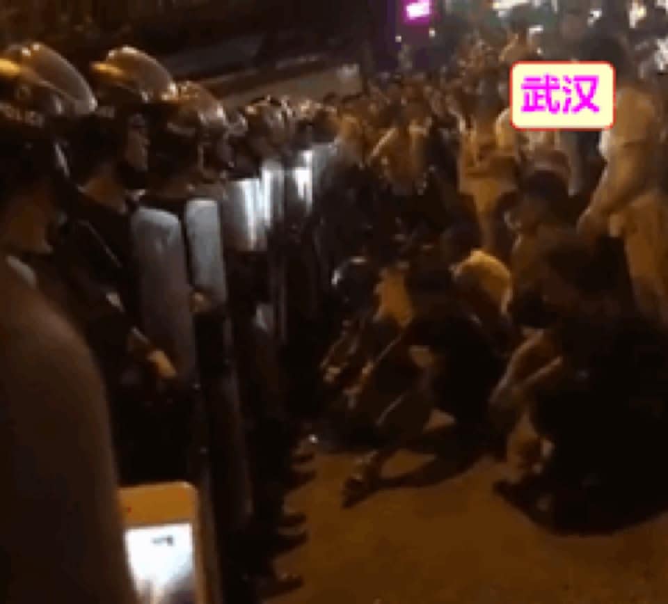 武漢民眾靜靜地坐在盾牌前，與政府對峙。 圖：翻攝自王丹臉書