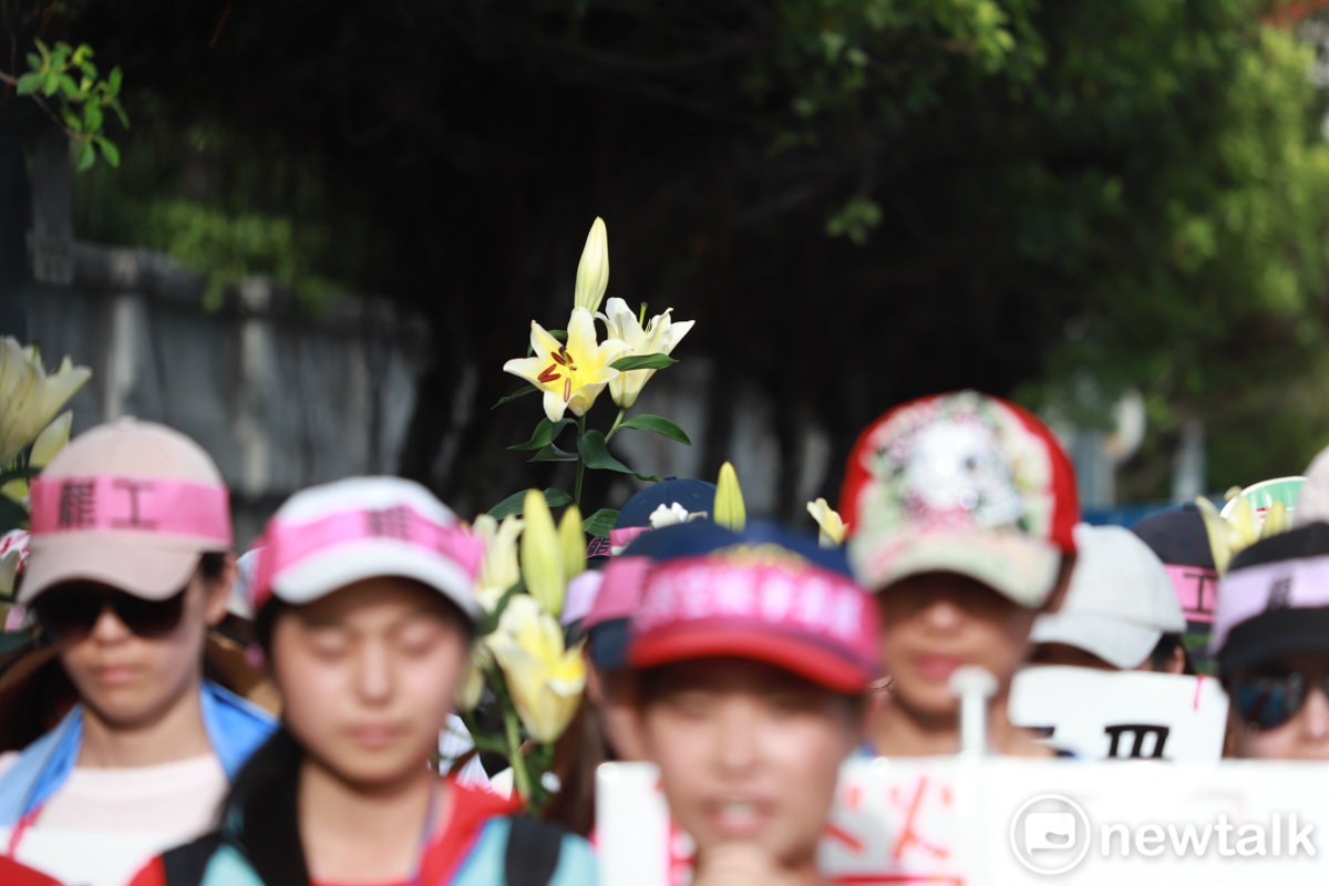 現場許多會員手捧百合花，站在工會代表後方。 圖：謝佳真／攝