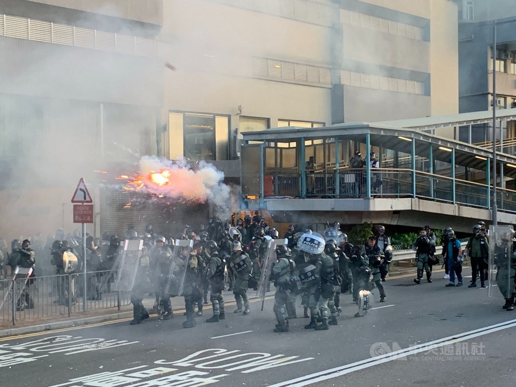 香港反送中自主遊行的部分示威人士，28日下午包圍中聯辦，港警派出大批防暴警察鎮守，並在晚間7時高舉黑旗、隨即施放催淚彈進行清場。 圖：中央社提供。