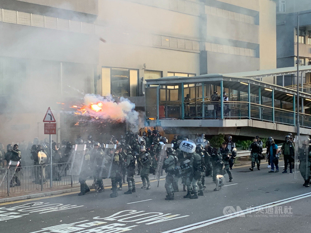 香港反送中自主遊行的部分示威人士，28日下午包圍中聯辦，港警派出大批防暴警察鎮守，並在晚間7時高舉黑旗、隨即施放催淚彈進行清場。 圖：中央社