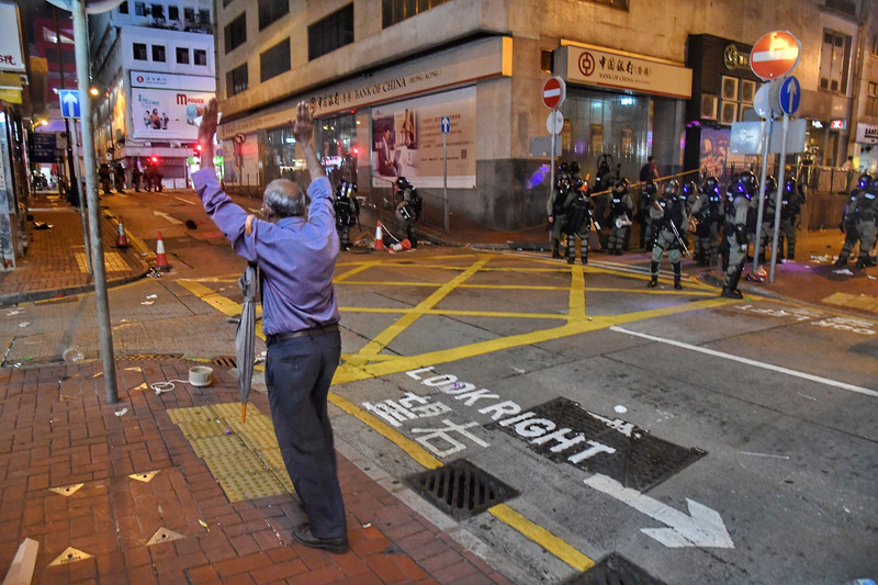 香港反送中活動28日持續延燒，港島市區猶如大型游擊戰場，大批警力晚間強勢驅離示威民眾，一名家住上環的市民深夜返家，看見鎮暴警察隨即高舉雙手，表明自己並非示威者。 圖 : 中央社