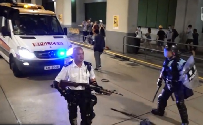 逾千港人30日晚間陸續前往葵涌警署抗議，部份示威者朝員警丟擲三角錐及雞蛋等物品，員警也發射胡椒噴霧還擊，並手持長槍指向人群。 圖：翻攝RTHK NEWS臉書影片