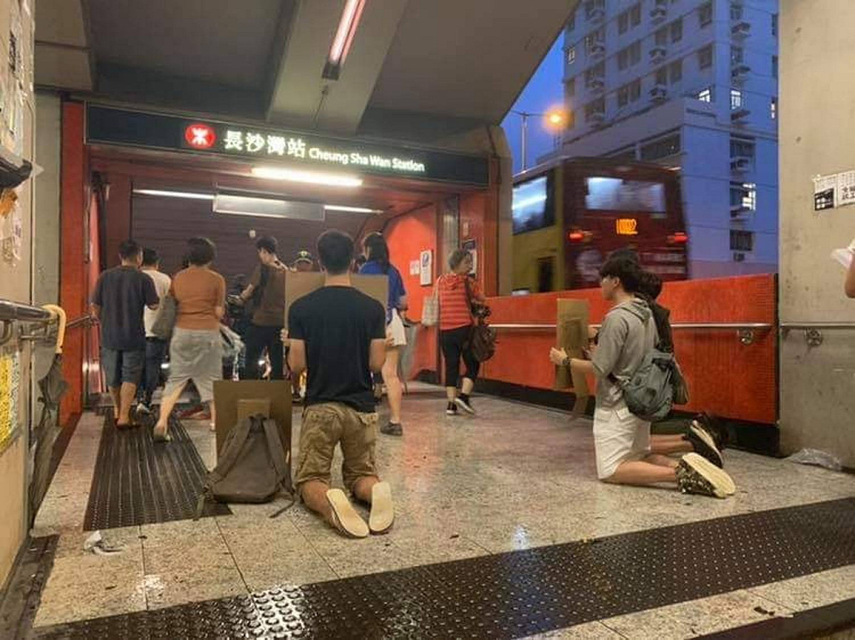 4名年輕人，到港鐵手持紙牌默跪，一跪就是好幾個小時，只為呼籲更多人參與罷工行列。 圖:擷取自fb群組「長沙灣街坊」圖片