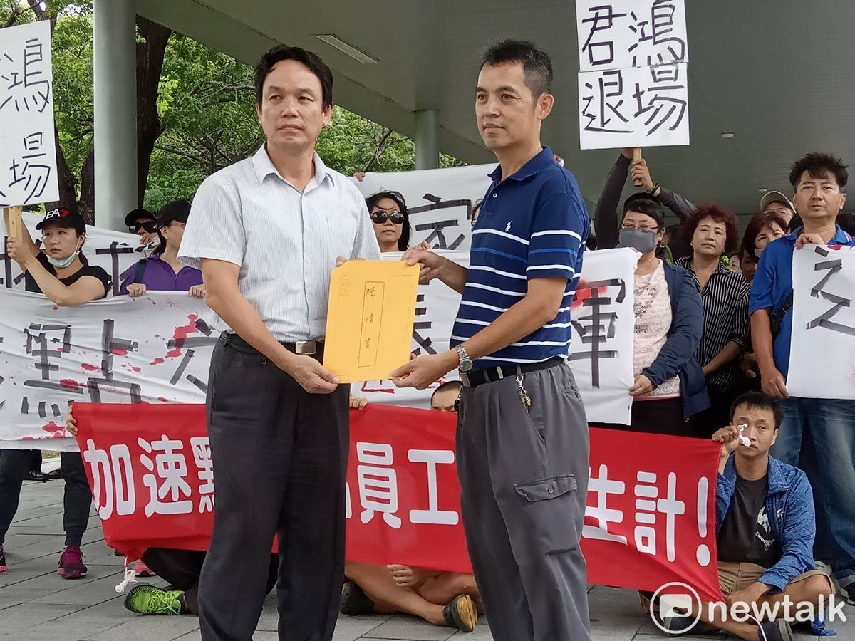 高市勞工局主秘皮忠謀(左)從自救團會長洪水木手中接下陳情書。 圖  :   孫家銘／攝